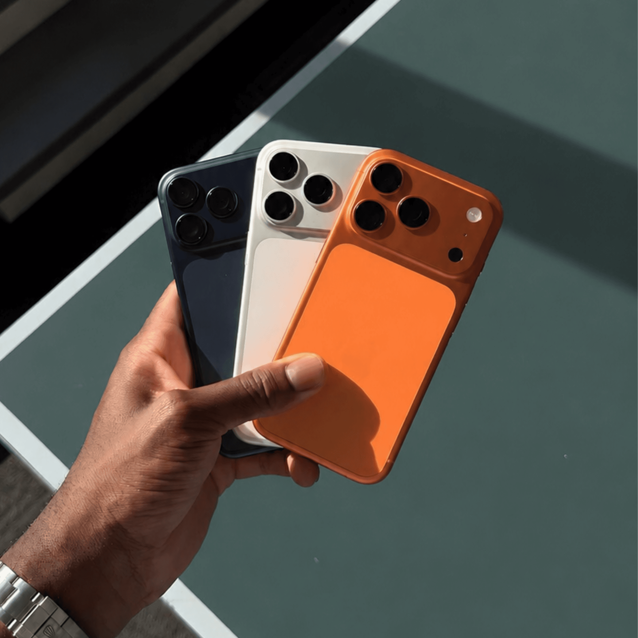 Tres iPhones vistos desde atrás sostenidos en una mano